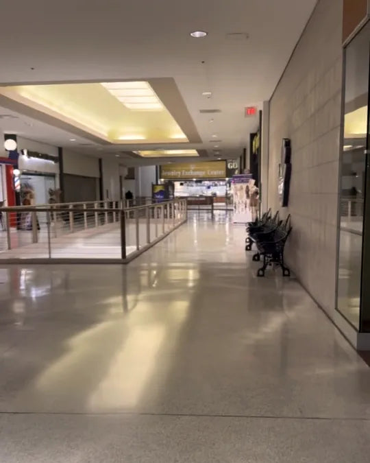 At the top of the escalator turn left — the second-floor walkway with the storefront wall bending right