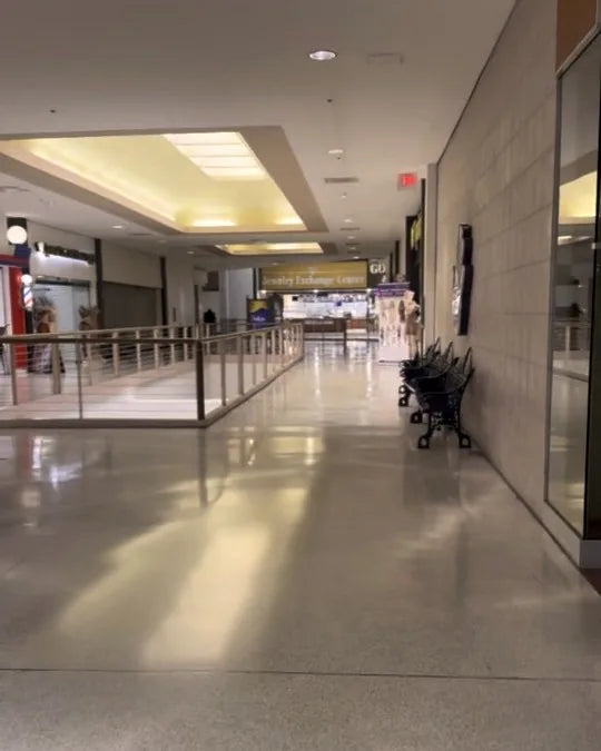 At the top of the escalator turn left — the second-floor walkway with the storefront wall bending right
